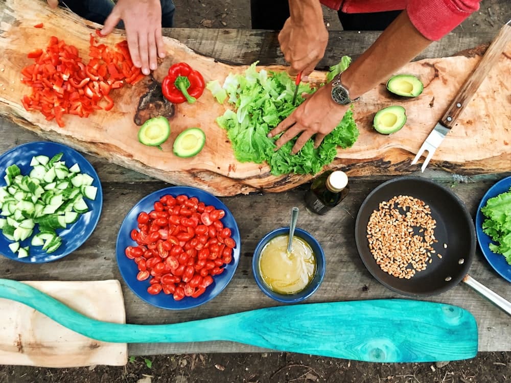 Hands prepping vegetables on a board.